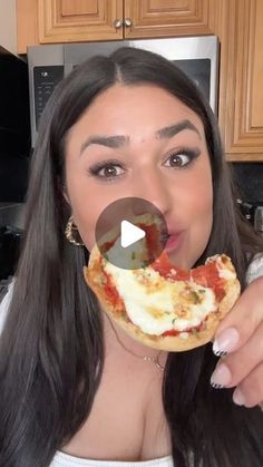 a woman making a funny face while holding a piece of pizza in front of her mouth