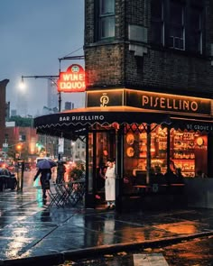 people are standing outside in the rain near a pizzeria and restaurant at night