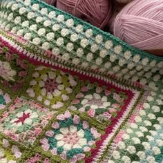 two balls of yarn sit on top of a crocheted granny's blanket