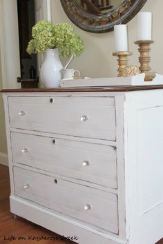 a white dresser with flowers and candles on top