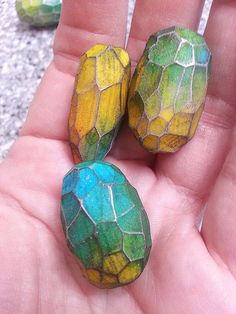 three different colored stones in the palm of someone's hand, one is yellow and green