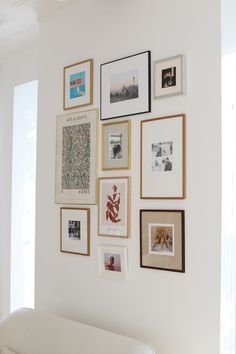 a white couch sitting under a wall covered in pictures and framed art on it's side