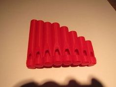 four red plastic objects sitting on top of a white table next to a black shadow