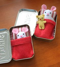 two tins filled with small stuffed animals inside of each other on a wooden table