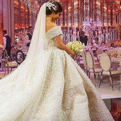 a woman in a wedding dress standing next to a table with chairs and chandeliers