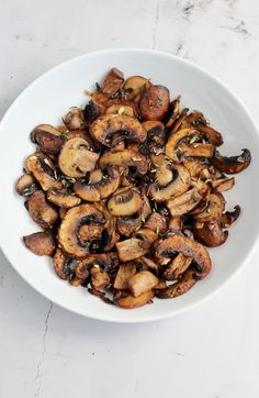 a white bowl filled with mushrooms on top of a table