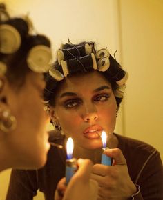 a woman holding a lit candle in front of her face