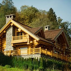 a log cabin with wooden balconies on the front and second story is surrounded by greenery