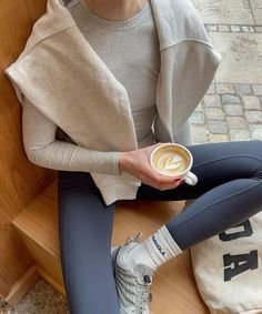 a woman sitting on a bench holding a cup of coffee