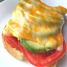 a sandwich with cheese, tomato and avocado on it sitting on a plate