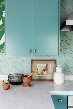 a kitchen with blue cabinets and white counter tops, including a framed painting on the wall