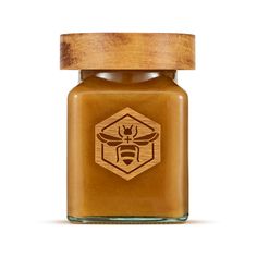 a honey jar with a wooden lid and a bee on it's side, in front of a white background