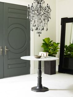 a chandelier hangs from the ceiling above a white table in front of a door