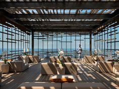 an outdoor seating area overlooking the ocean with sun shining through the windows and wooden flooring