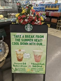 a sign advertising cold drinks in a starbucks coffee shop with flowers on the counter top