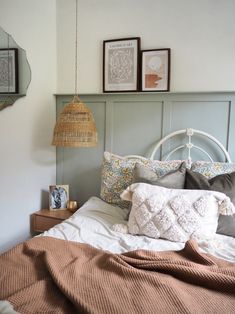 a bed with pillows, blankets and pictures on the wall above it in a bedroom