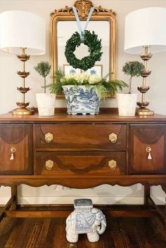 a wooden dresser sitting in front of a mirror with two lamps on top of it