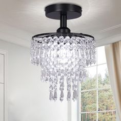 a chandelier hanging from the ceiling in a room with white walls and windows