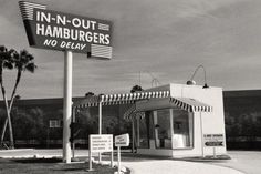 a black and white photo of a restaurant with a sign that says in - n - out hamburgers