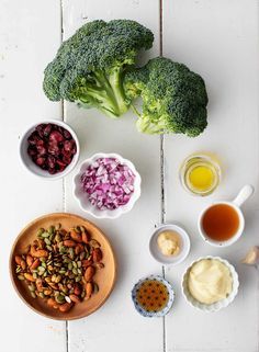 broccoli, carrots, nuts, and other foods are arranged on a white table