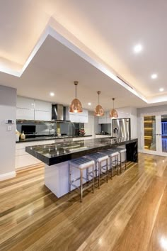 a kitchen with an island and bar stools next to it on a hard wood floor