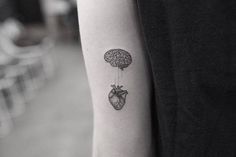 a person with a tattoo on their arm has a heart and brain attached to it