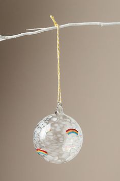 a glass ornament hanging from a twig with a rainbow painted on it