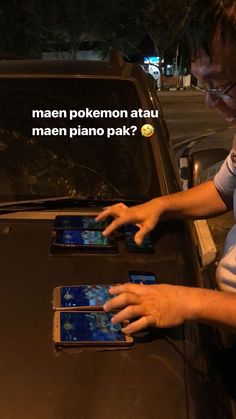 a man holding two cell phones in front of a car with the words mean pokemon atau men piano pak?