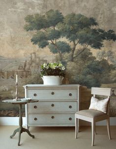 a white dresser sitting next to a table with a potted plant on top of it