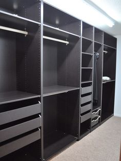 an empty walk in closet with lots of black drawers and bins on the shelves