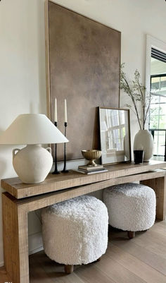 a console table with two stools and a lamp