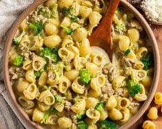 a wooden bowl filled with pasta and broccoli