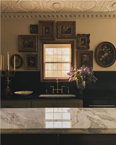 a kitchen with marble counter tops and pictures on the wall above it's sink