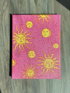 a pink napkin with sun and moon designs on it sitting on top of a wooden table