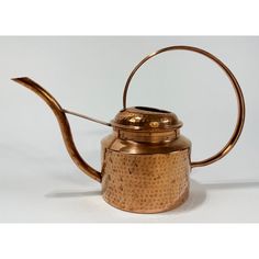 a copper colored tea pot with a metal handle