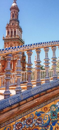 an intricately painted wall with a clock tower in the background and blue tiles on it