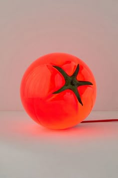 an orange ball with a green star on it sitting in front of a white background