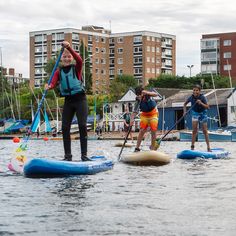 several people on surfboards in the water with buildings in the backgrouds