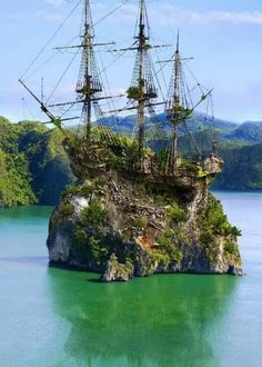 an old pirate ship floating on top of a rock in the middle of a body of water