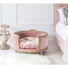 a pink chair sitting on top of a white rug next to a bed and vase