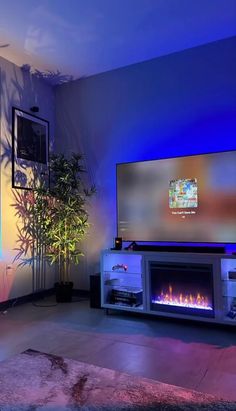 a living room with a large television and fire place in the center, lit by blue lights