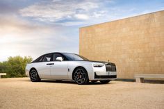 a white rolls royce parked in front of a building with a bench on the side