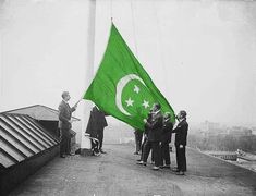 some people are holding a green flag on top of a building