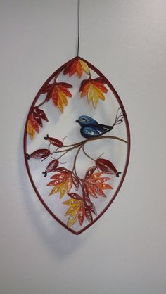 a bird is sitting on a branch with leaves in the shape of a circle hanging from a hook