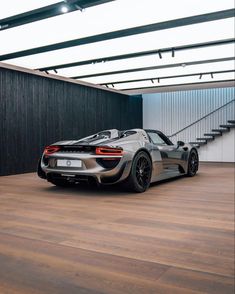 a silver sports car parked in front of a building with wooden floors and black walls