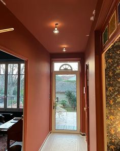 an empty hallway leading to the front door and dining room with large windows on both sides