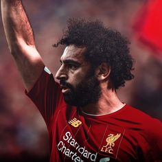 a man with curly hair and beard waves to the crowd at a soccer game in liverpool, england