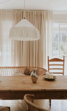 a wooden table with two chairs and a light hanging from the ceiling in front of a window