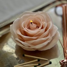 a pink rose sitting on top of a table next to matches