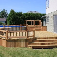 a wooden deck next to a swimming pool in a backyard with steps leading up to it